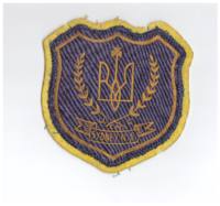 Blue Cloth Badge on yellow felt material; Badge has a trident with a cross on the top on either side laurel branches, underneath the branches the initials U.C.M.C (Ukrainian Catholic Men's Club) and Sydney, N.S