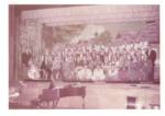 Photograph of performers and orchestra at new Ukrainian Hall with village back drop.